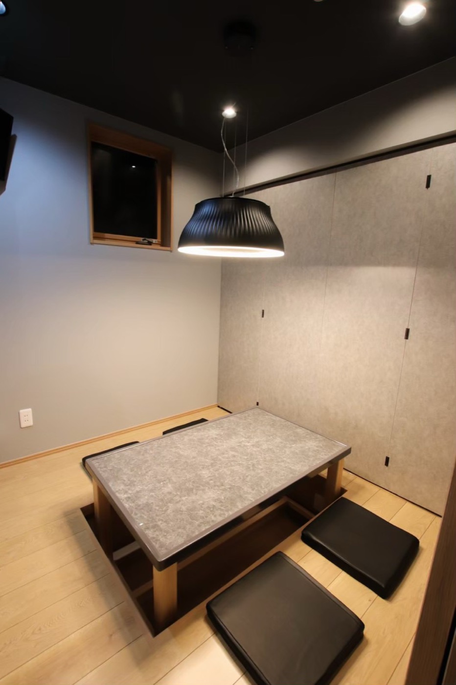半個室の掘りごたつ席。黒い提灯型ペンダントライトが低いテーブルを照らす